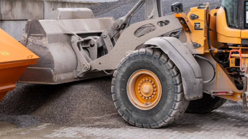 A heavy-duty yellow loader scooping gravel at a European construction site for road development.
