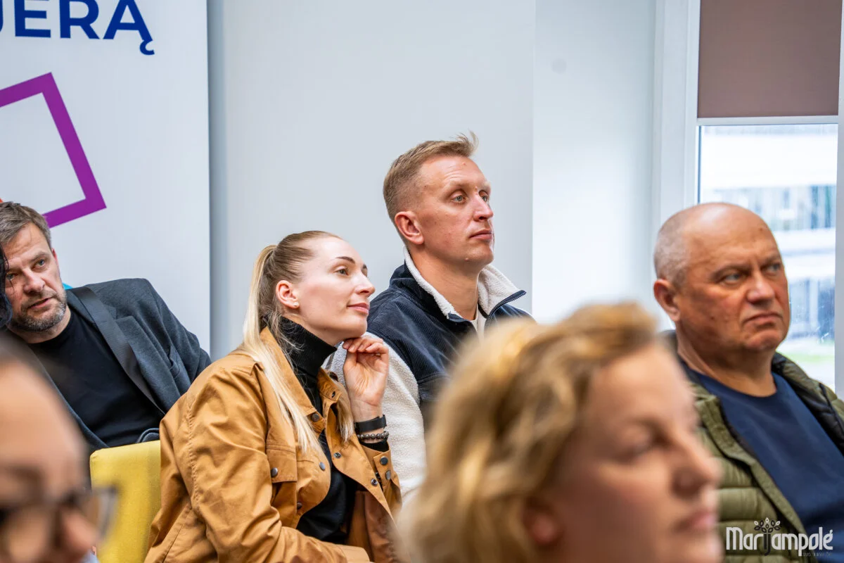 People sitting in an audience listening attentively during a seminar or local community presentation.