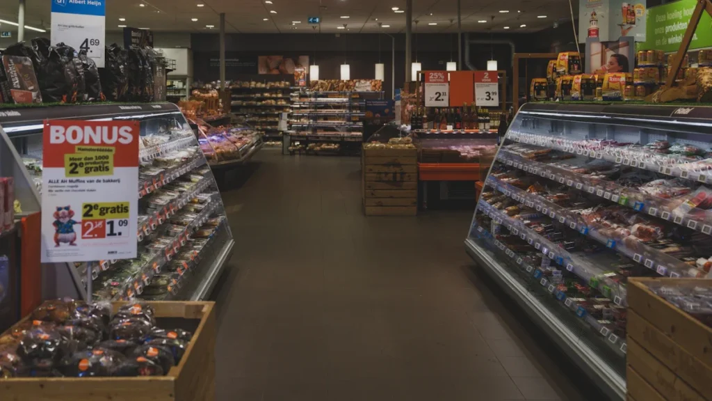 A wide-angle shot of a supermarket aisle with refrigerated display cases containing packaged food.