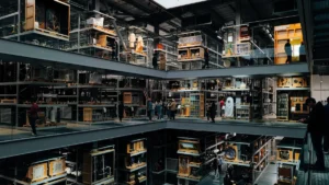 A wide, high-angle view of a modern, multi-level archival storage facility with industrial shelving and glass display cases containing historical objects.