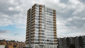 A high-rise residential tower block under a cloudy sky, representative of UK social housing.