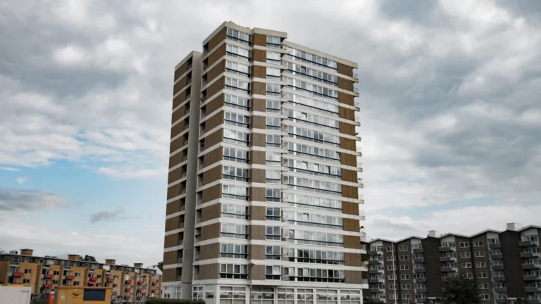 A high-rise residential tower block under a cloudy sky, representative of UK social housing.