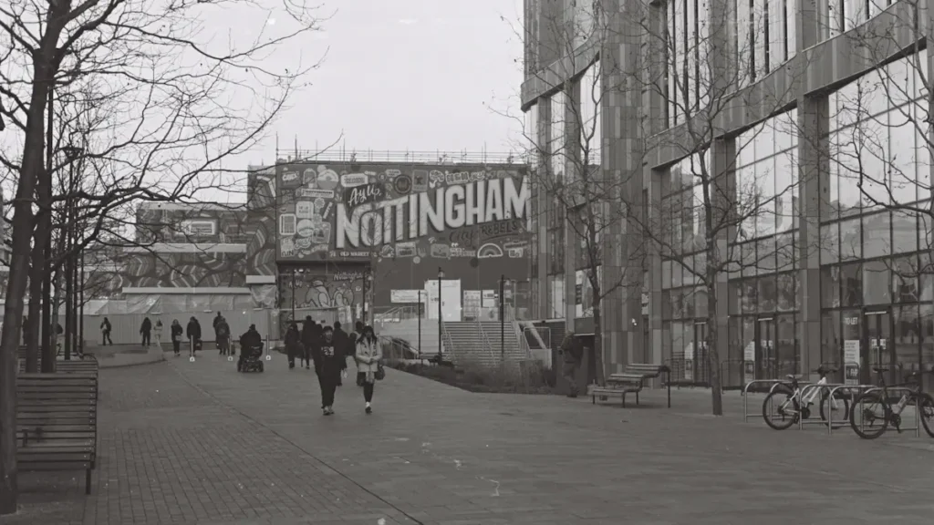 Black and white street scene featuring a large sign reading Nottingham in city center.