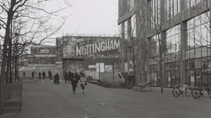 Black and white street scene featuring a large sign reading Nottingham in city center.