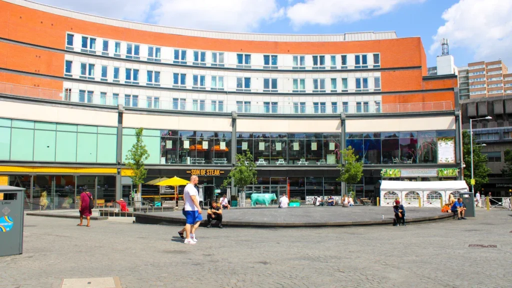 A busy public square in Nottingham with historic brick architecture and urban life.