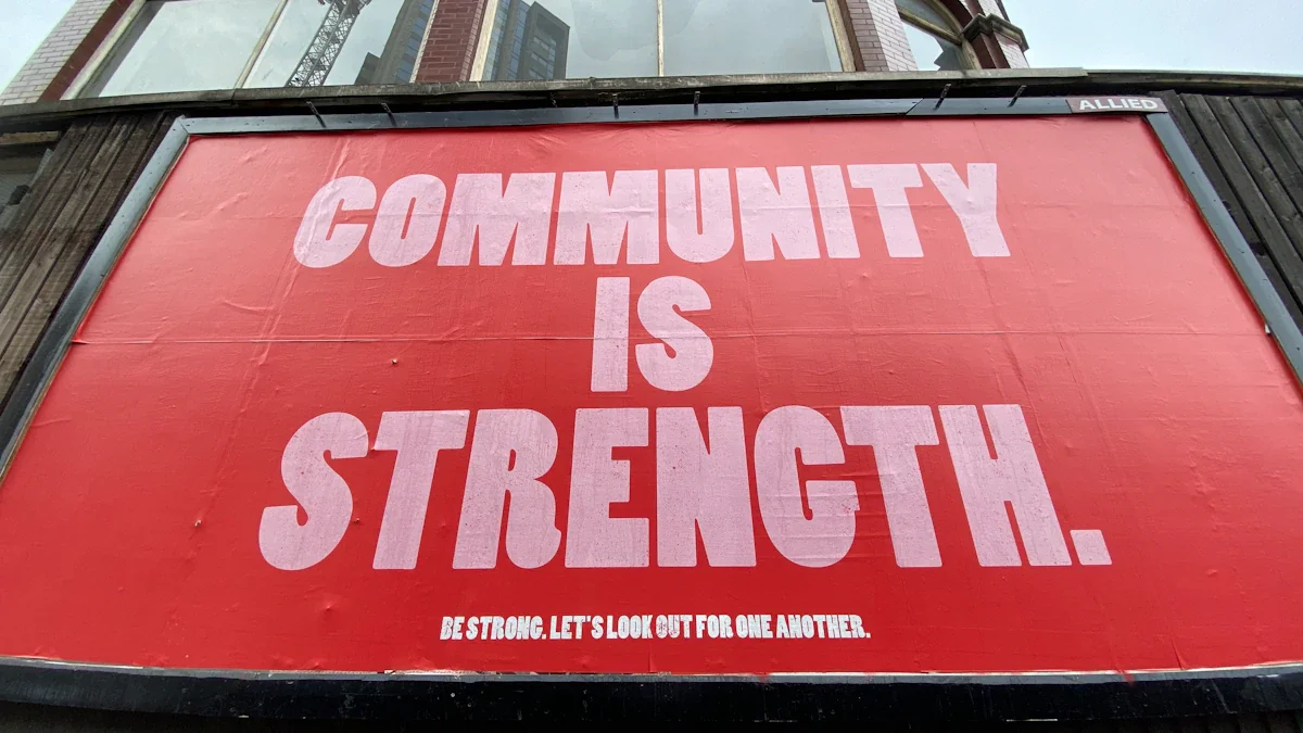 A bold red sign on a London building reading Community is Strength.