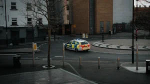 A British police car with yellow and blue Battenburg markings patrolling a London street.