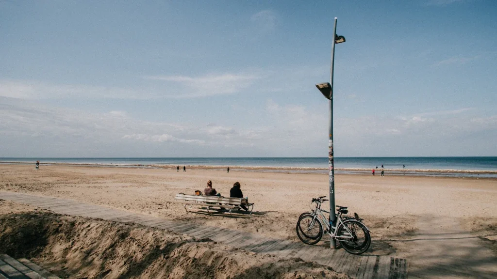 Two people sitting on a bench on a wide sandy beach in Jurmala near Riga, Latvia.