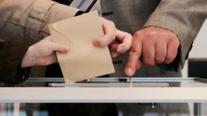 A voter casting their ballot into a ballot box at a polling station.
