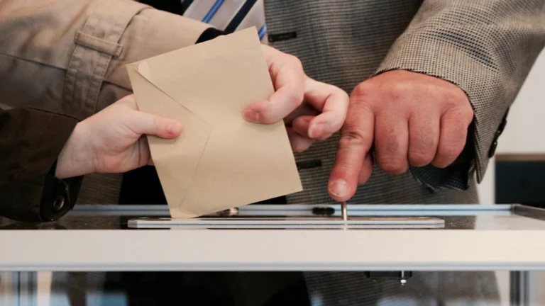 A voter casting their ballot into a ballot box at a polling station.
