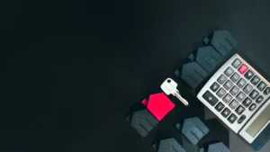 A silver key, a calculator, and house-shaped models arranged on a dark surface to represent housing policy and tenant rights.
