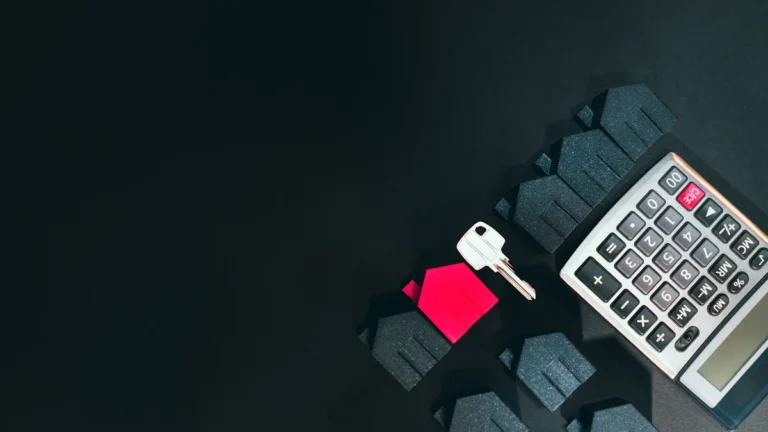 A silver key, a calculator, and house-shaped models arranged on a dark surface to represent housing policy and tenant rights.