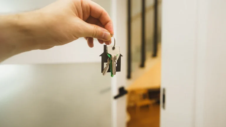A hand holding house keys with a house-shaped keychain in a home hallway, representing new renter protections in Sefton.