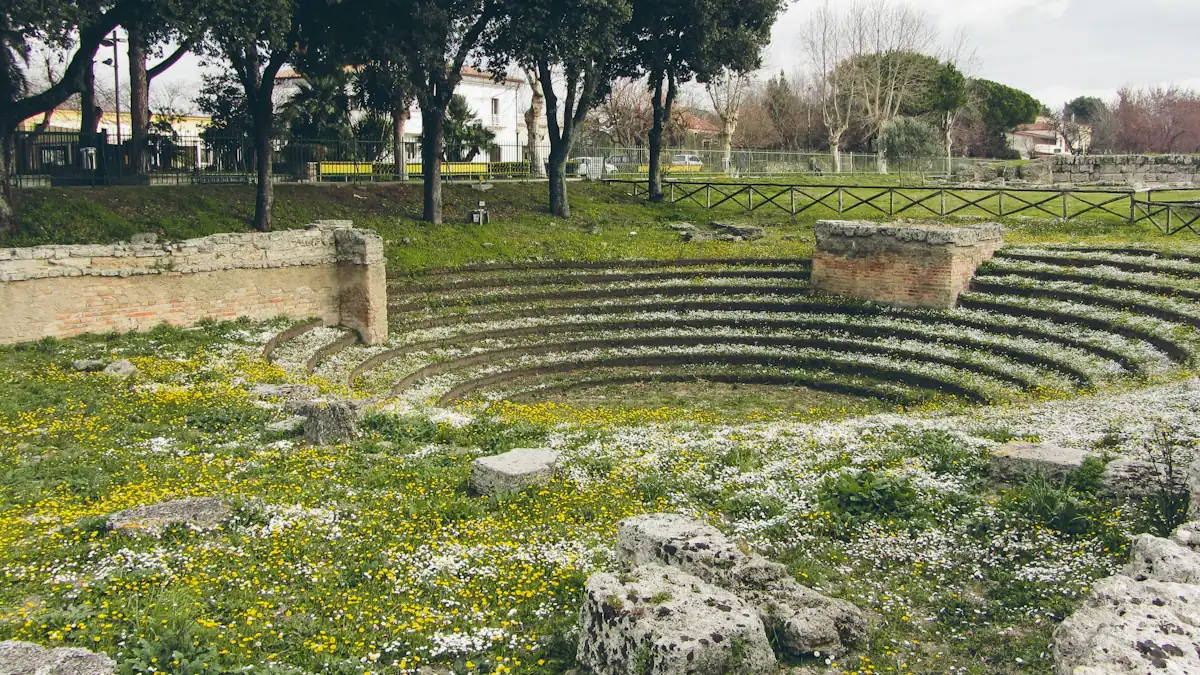 Ancient stone structure of the Ekklesiasterion in a lush green field in Italy