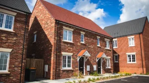 Modern red brick semi-detached houses under a bright blue sky on a UK housing estate.