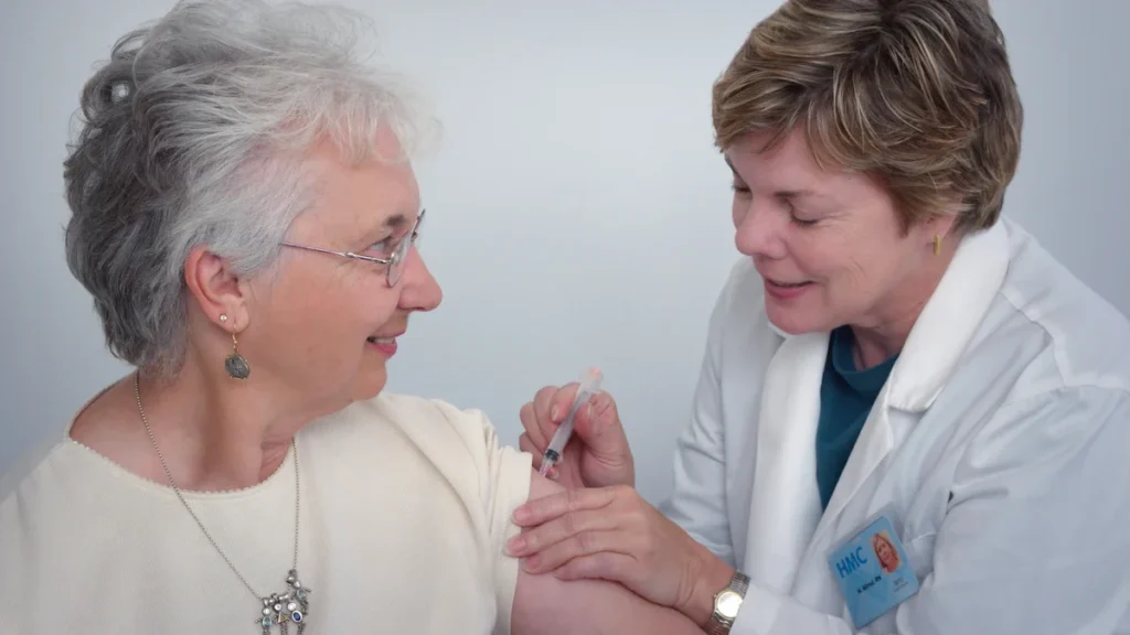 A healthcare professional administers a COVID-19 booster vaccine to an elderly woman in a clinical setting.