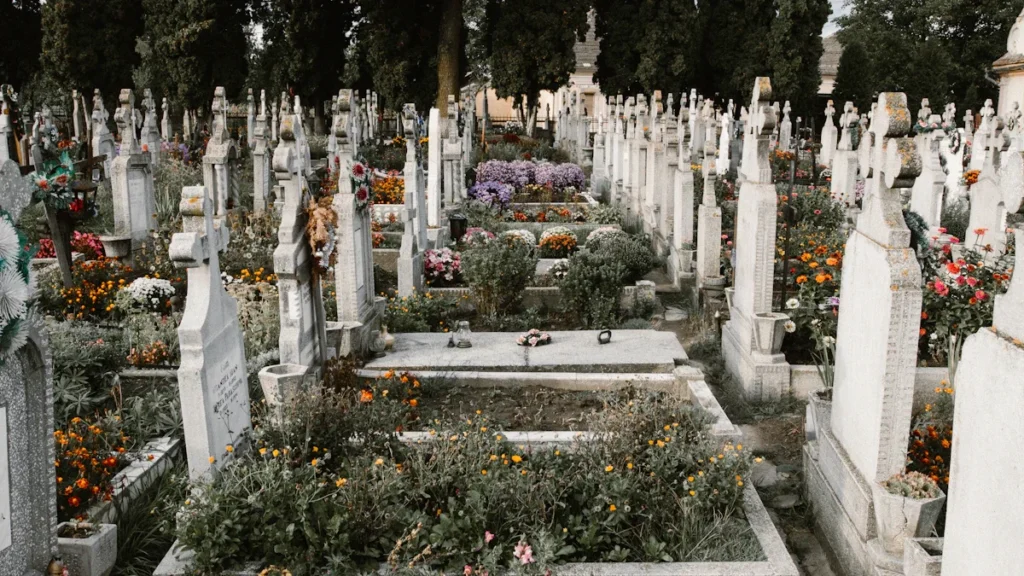 A wide view of a well-maintained cemetery with numerous stone crosses and colorful flowers in bloom.