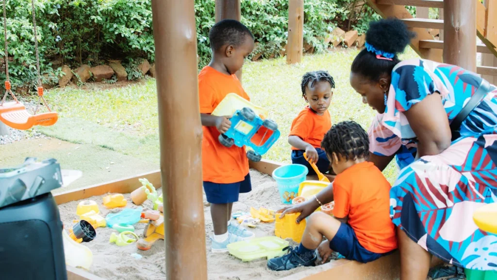 A group of children playing in a sandbox with an adult at a community support center in Stockport.