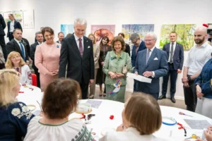 President Nausėda and Swedish royals observe people working at a craft table in a gallery.