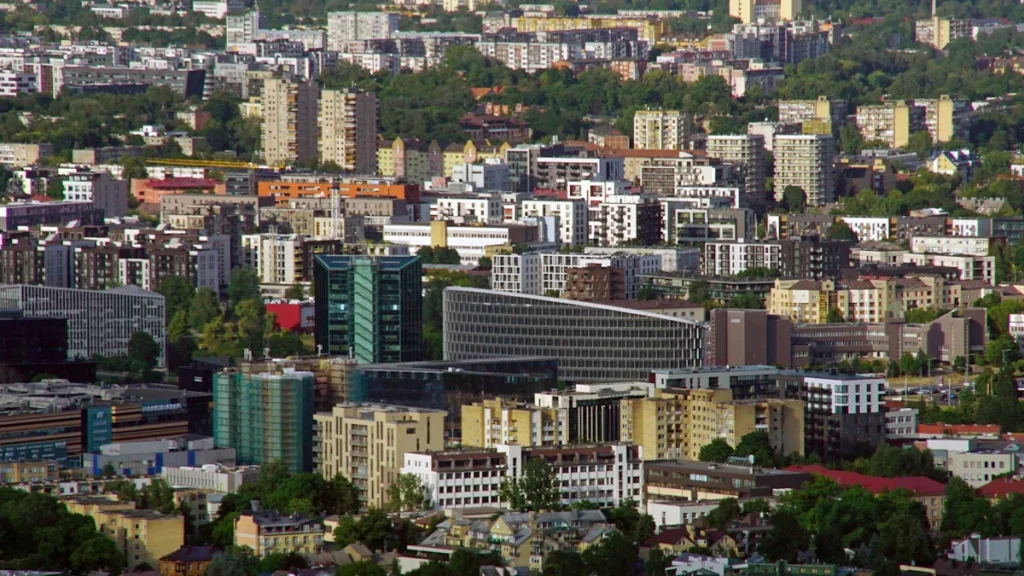 An expansive aerial view of the Vilnius city skyline and residential neighborhoods during a summer evening.