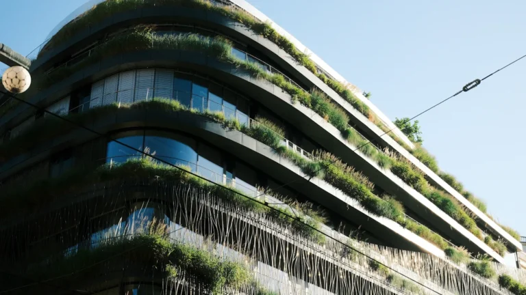 Modern architectural structure featuring tiered balconies overflowing with lush green trees and vertical gardens.
