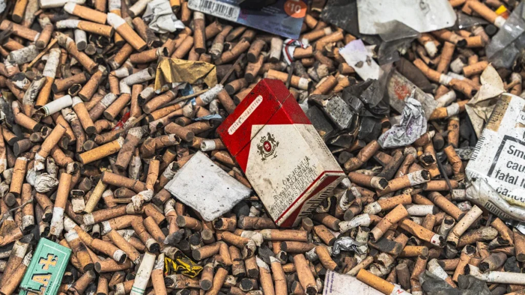 A chaotic pile of hundreds of cigarette butts surrounding a discarded red cigarette pack.