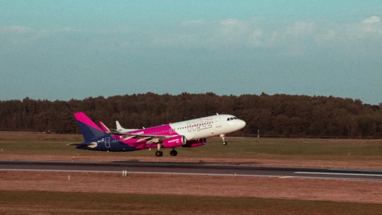 A Wizz Air passenger jet taking off from the runway at Vilnius Airport against a clear sky.