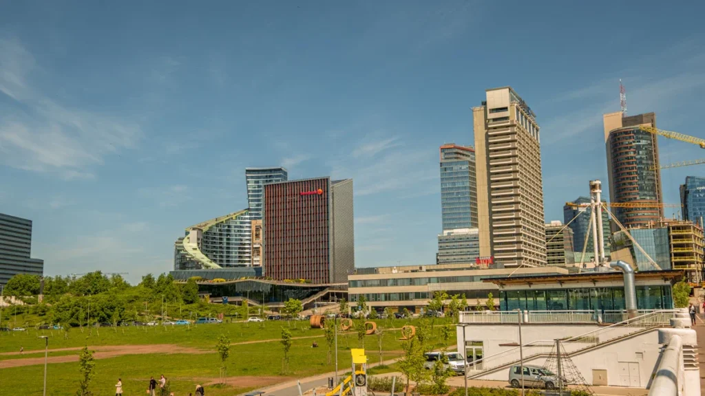 The modern skyline of Vilnius, Lithuania, featuring contemporary glass office buildings and a green urban park.