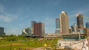 The modern skyline of Vilnius, Lithuania, featuring contemporary glass office buildings and a green urban park.