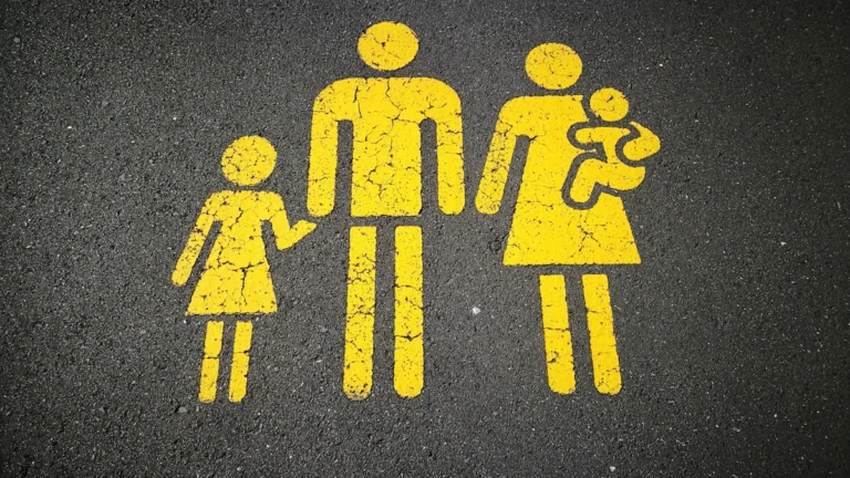 A yellow stencil of a family painted on dark asphalt, representing local support services for parents.