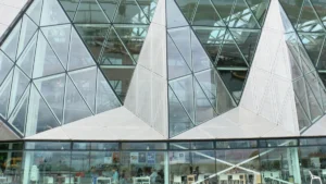 A modern building featuring a geometric glass facade and a community cafe visible through the windows.