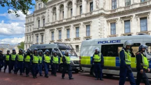 A large group of police officers in high-visibility vests walking past a historic London building.