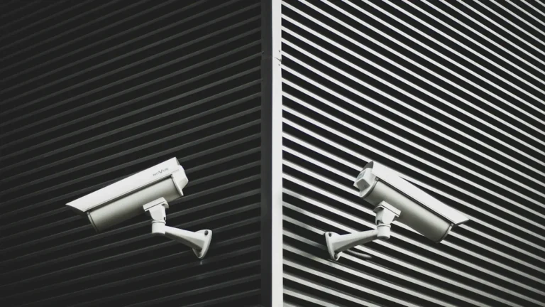 Two black and white CCTV security cameras mounted on a modern metal building corner.