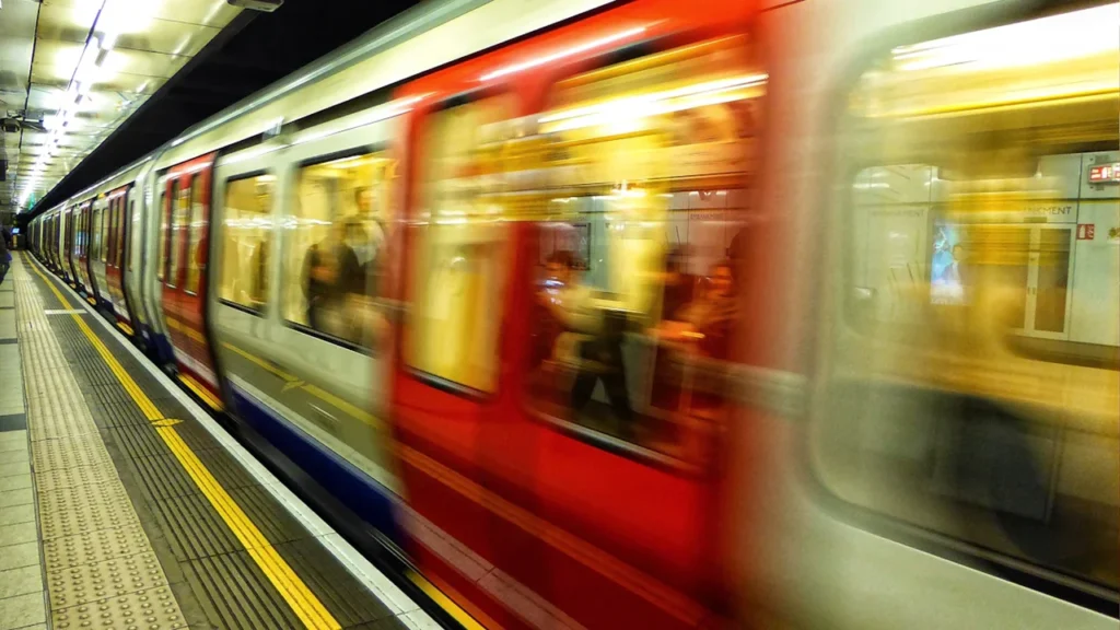 An underground train speeding into a London station with motion blur.