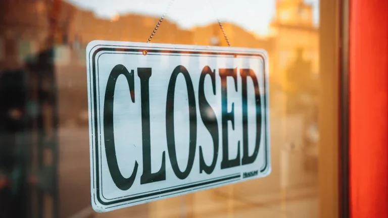 A close-up shot of a closed sign hanging on a shop glass door.