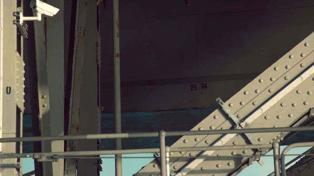 Close-up of a security camera mounted on a steel bridge structure.