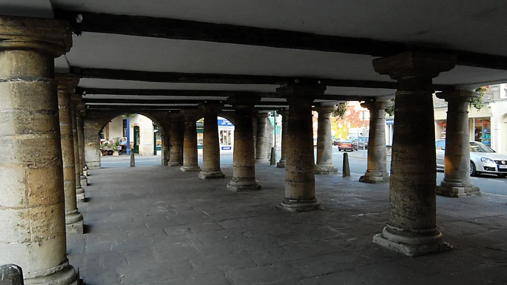 The historic stone pillars of a traditional English covered market hall walkway.