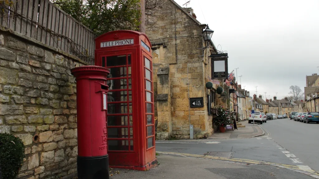 Classic red British telephone box and post box on a quiet English street.