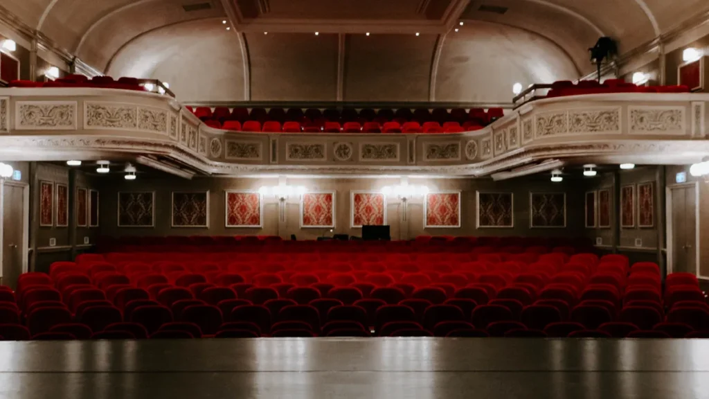 An ornate historic theater auditorium with classic balcony seating and closed stage curtains.