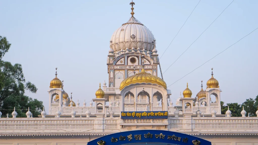 A serene view of a large white Sikh temple with golden domes.