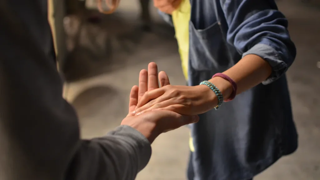 Two hands meeting palm to palm in a gesture of human connection and support.