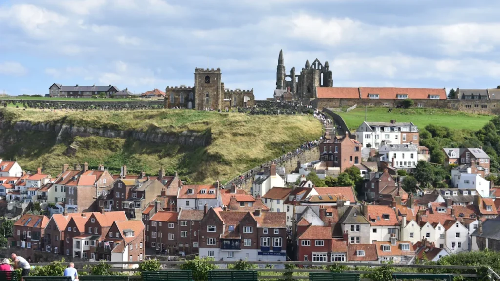 Aerial view of Whitby seaside town with green hills and traditional British housing.