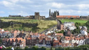 Aerial view of Whitby seaside town with green hills and traditional British housing.