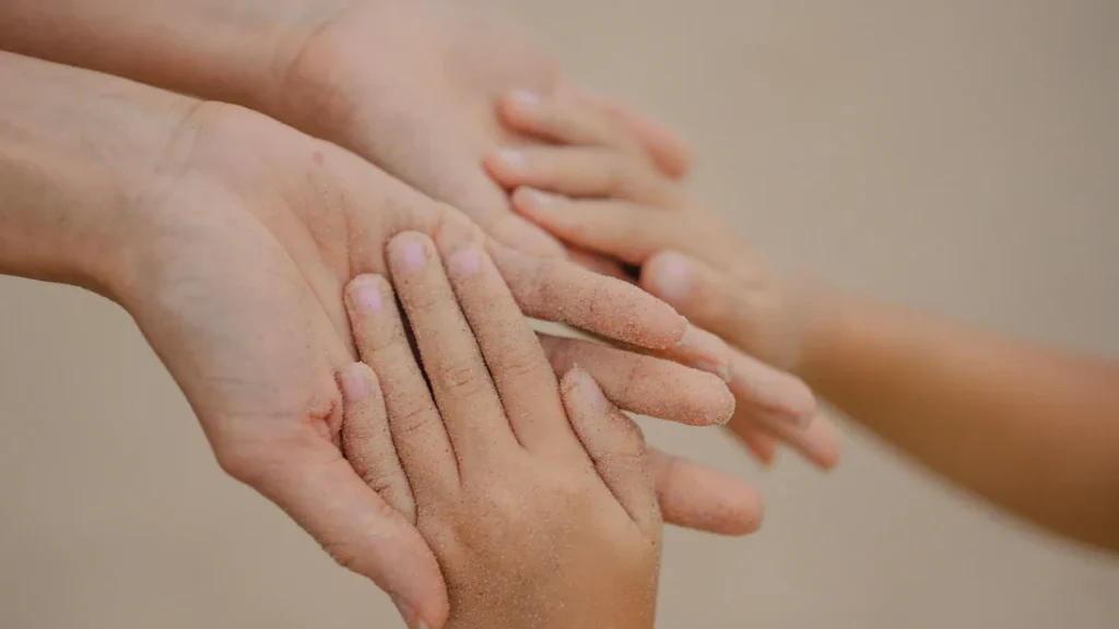 Close up of hands of different sizes held together in a supportive gesture.