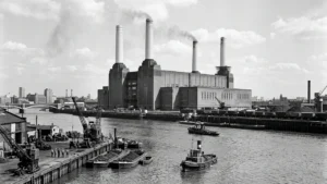 The iconic Battersea Power Station in London with smoke rising from its four tall chimneys.