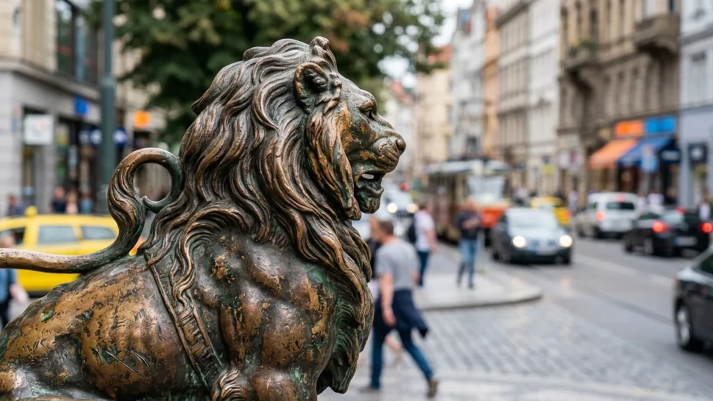 Close-up of a weathered bronze lion statue on a busy city street background.