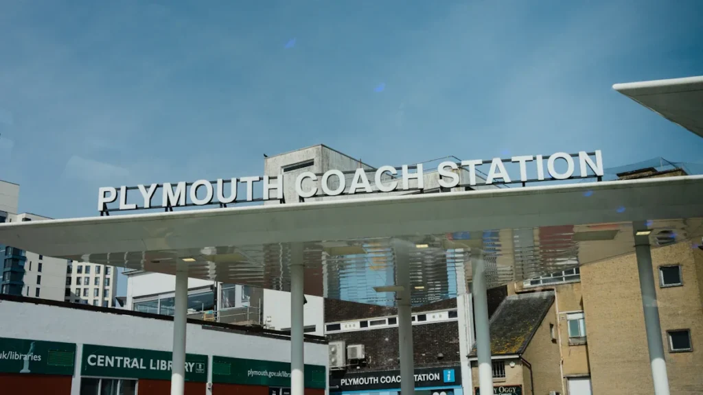 The exterior sign of Plymouth Coach Station under a clear blue sky.