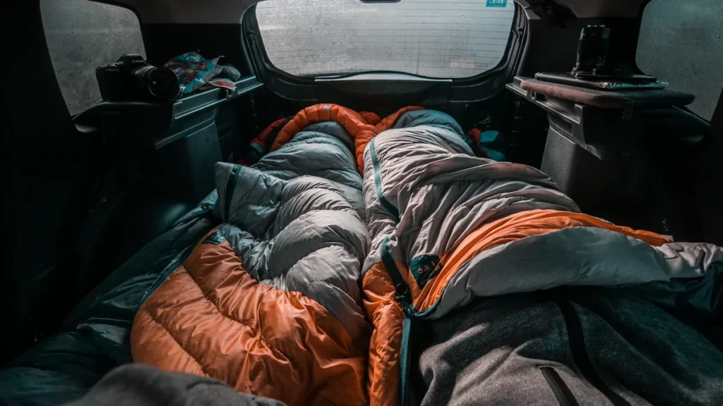 Sleeping bags arranged inside a car representing emergency accommodation and temporary shelter.