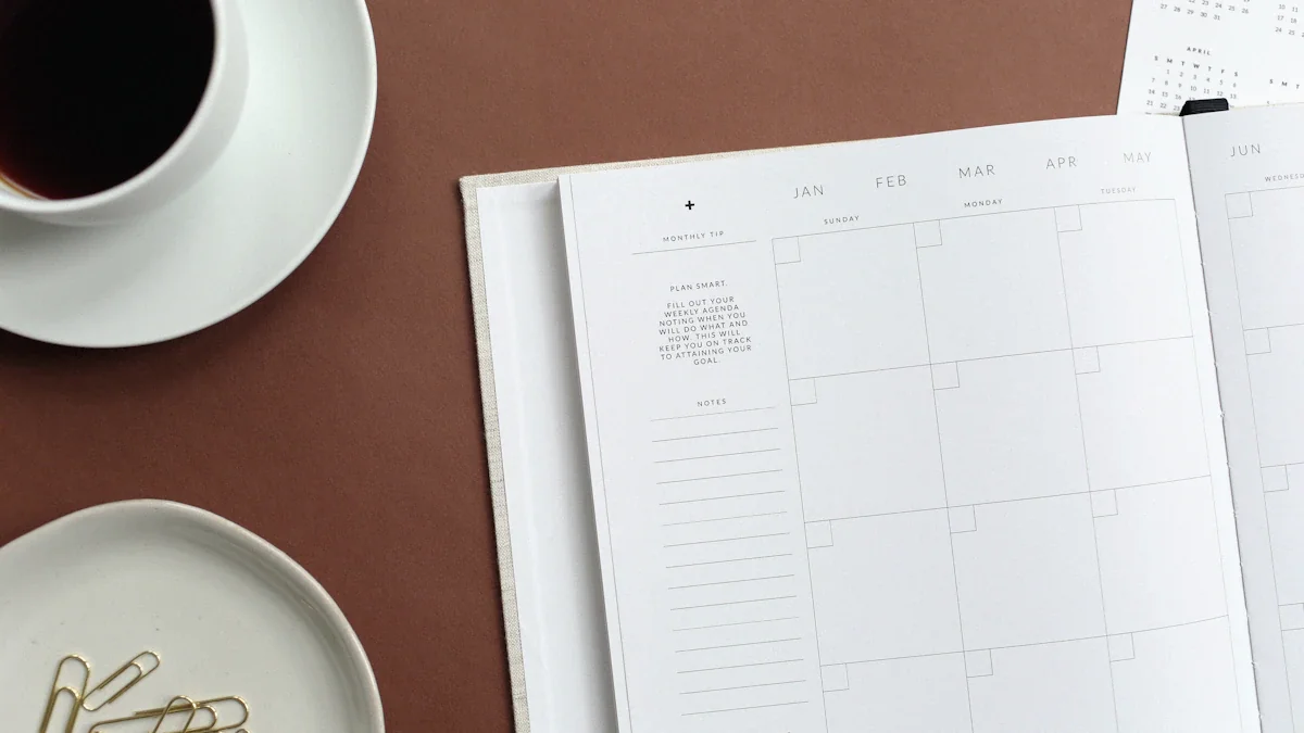 An open monthly planner beside a cup of tea and paper clips.