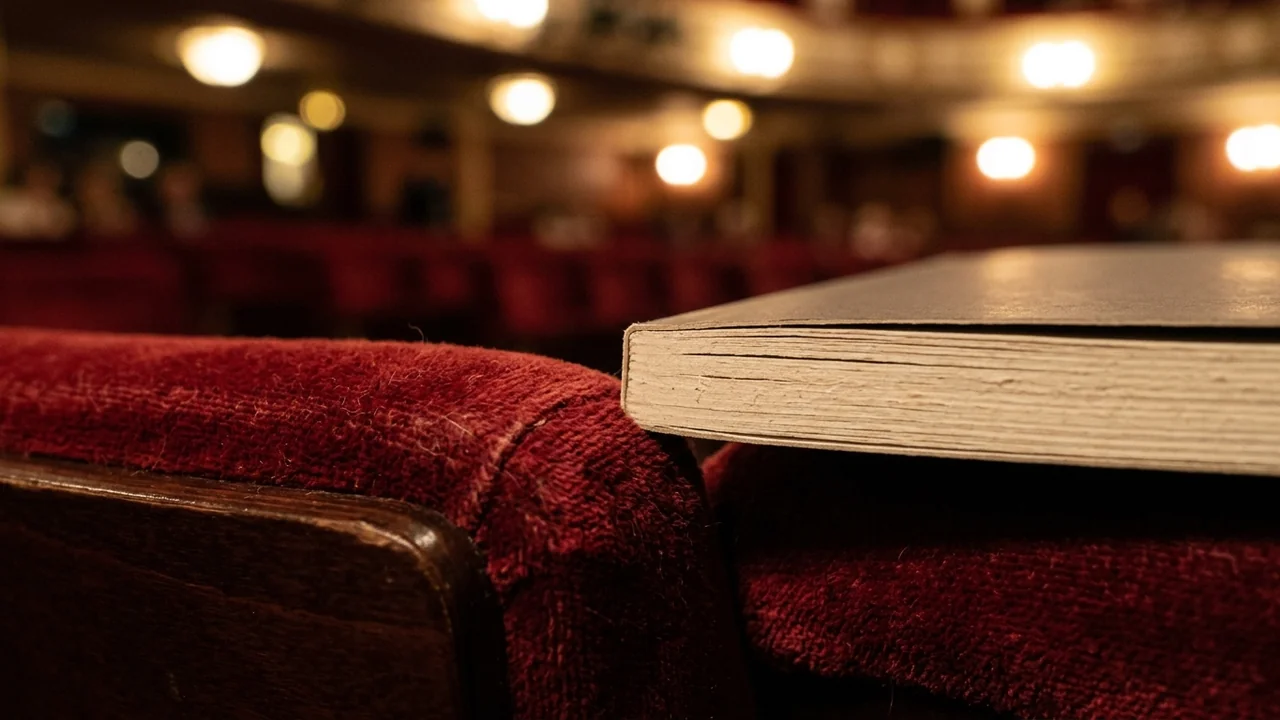 A script or playbill resting on a red velvet theater seat before a show.